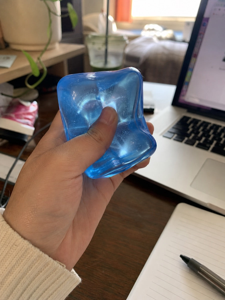 A blue sensory toy beside a laptop and notebook