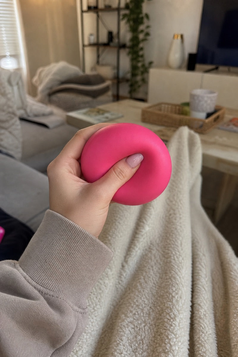 A pink sensory toy held while relaxing on a sofa